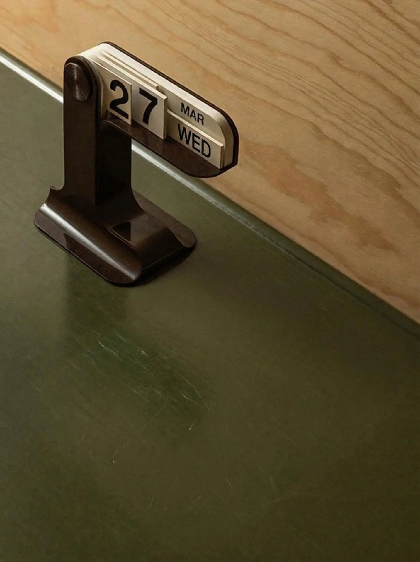 Calendar clip on a green surface with wooden background