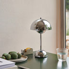 Silver table lamp on a desk with a glass of water and fruit