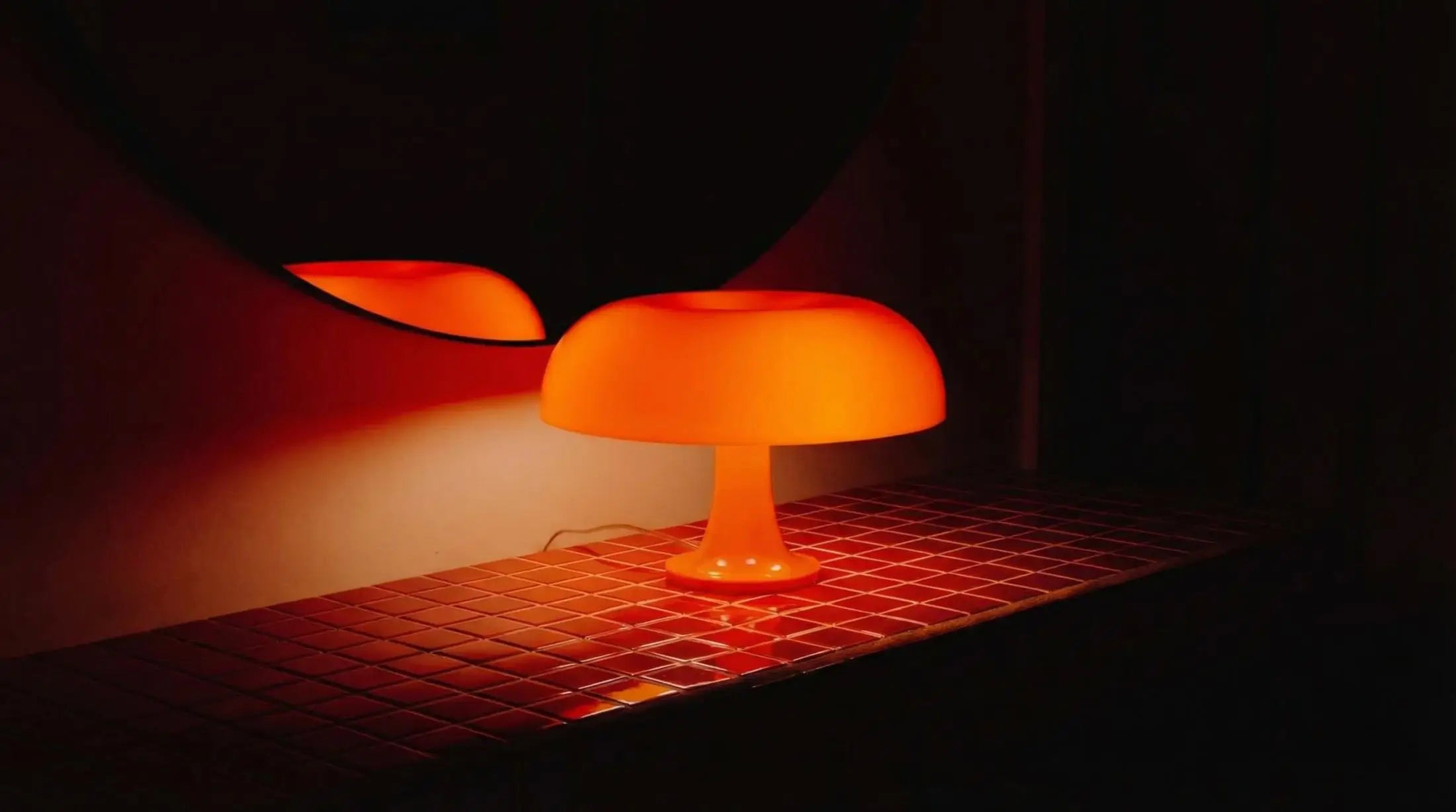 Orange table lamp on a dark surface with a blurred background