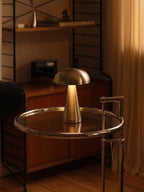 Modern interior with a metallic lamp and round table in a dimly lit room.