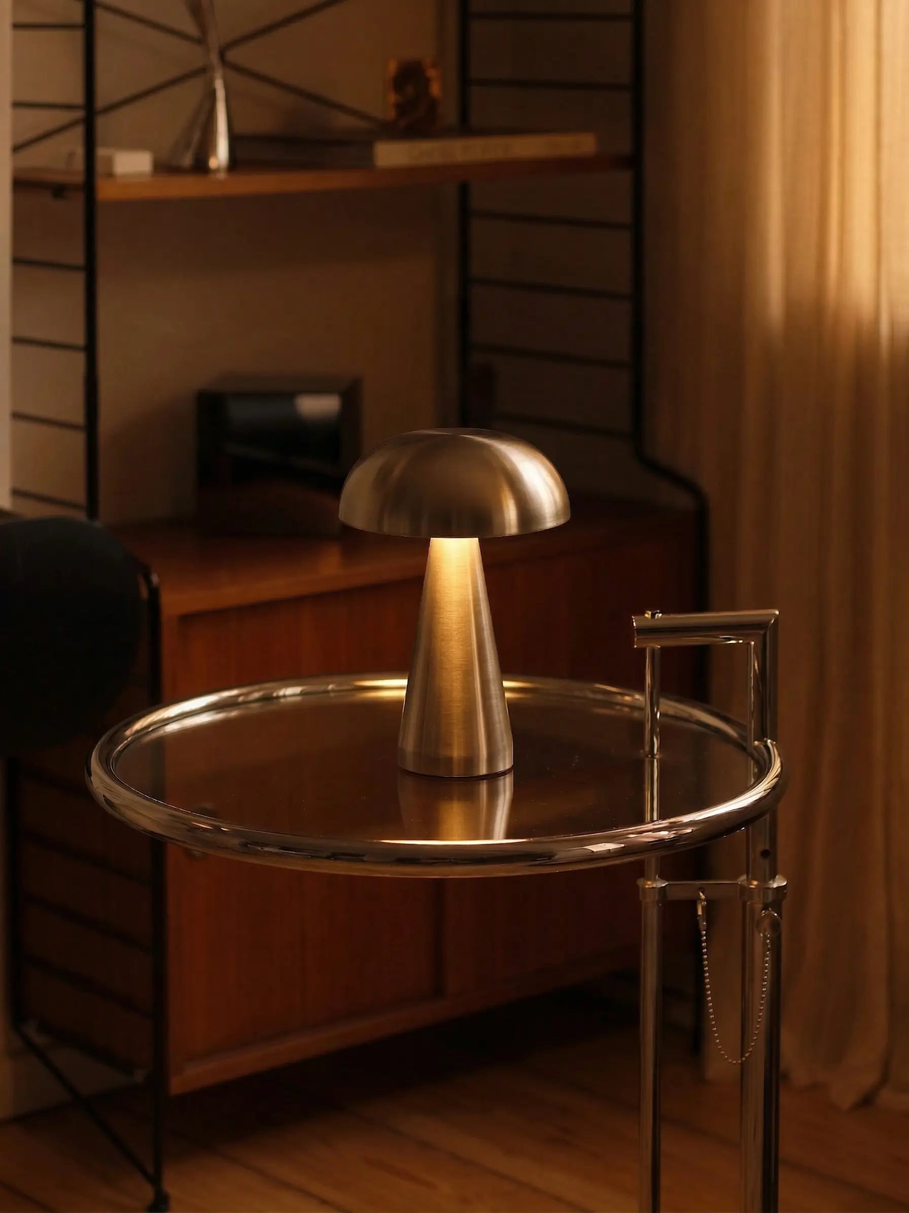 Modern interior with a metallic lamp and round table in a dimly lit room.