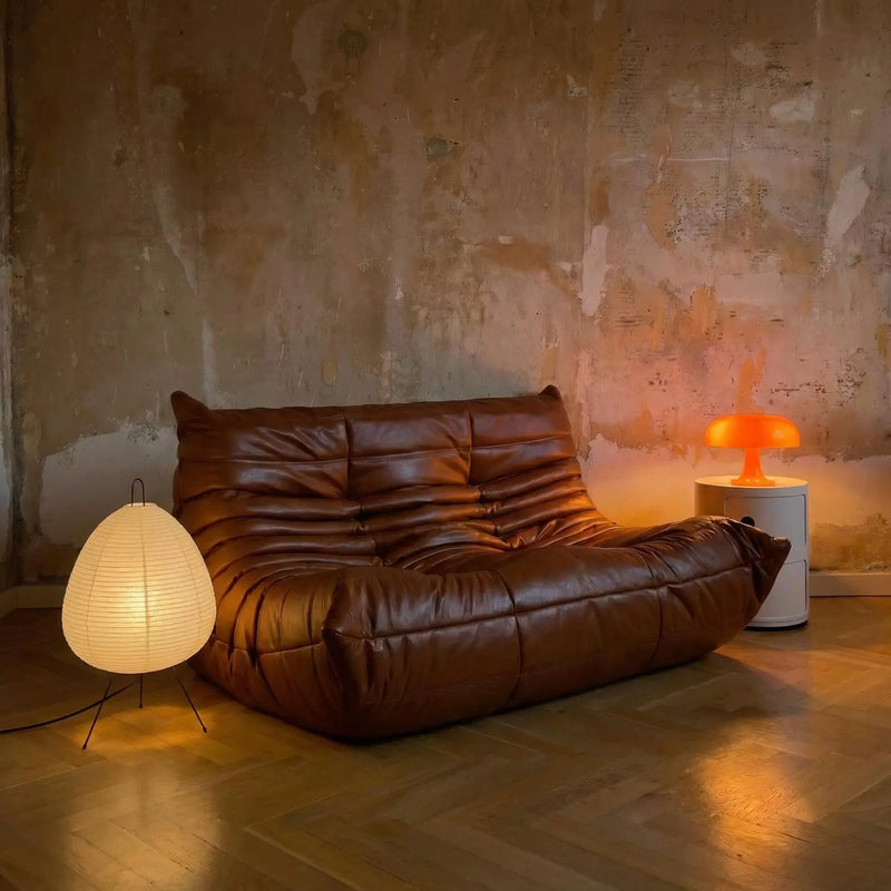Brown leather sofa in a room with textured walls and floor lamps.