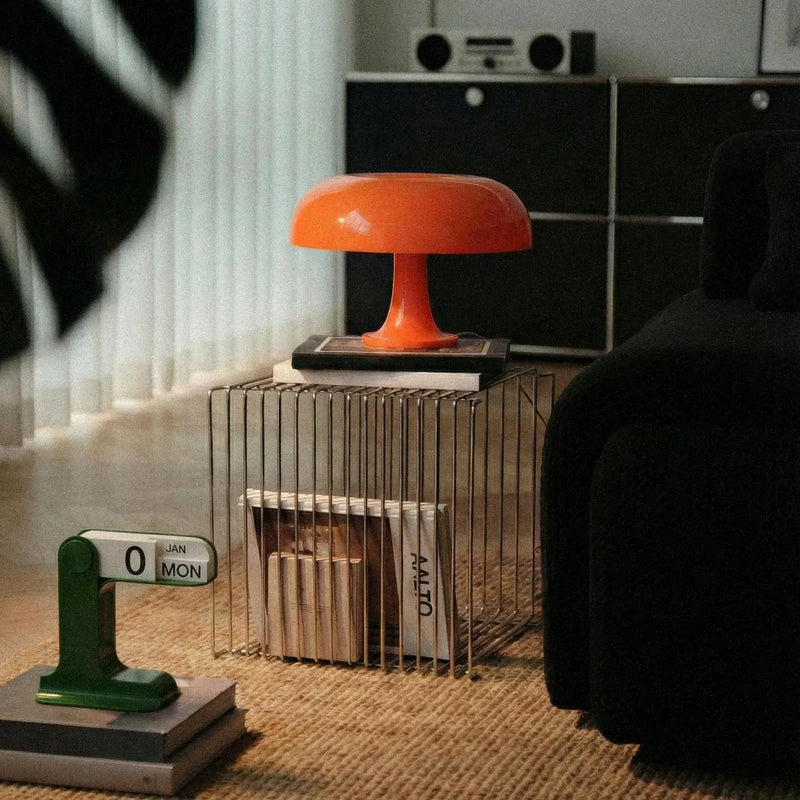 Orange lamp on a side table with a calendar and books in a room setting.